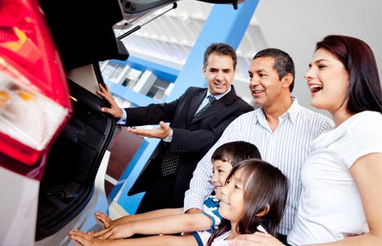 Salesperson with a family at a car dealership looking at a car