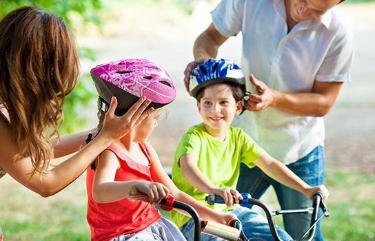 Parents putting safety bike helmets on kids